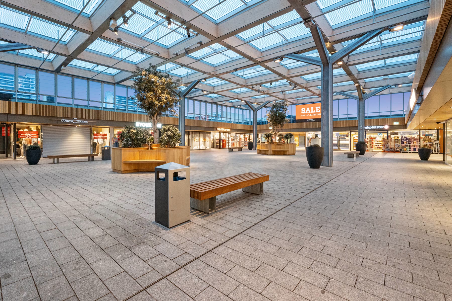 Avondopname van een winkelcentrum met glazen atrium